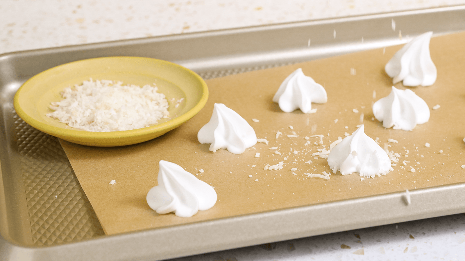 Haagen Dazs Pineapple Coconut Ice Cream Meringue Sandwiches on a tray with a plate of coconut shreds.